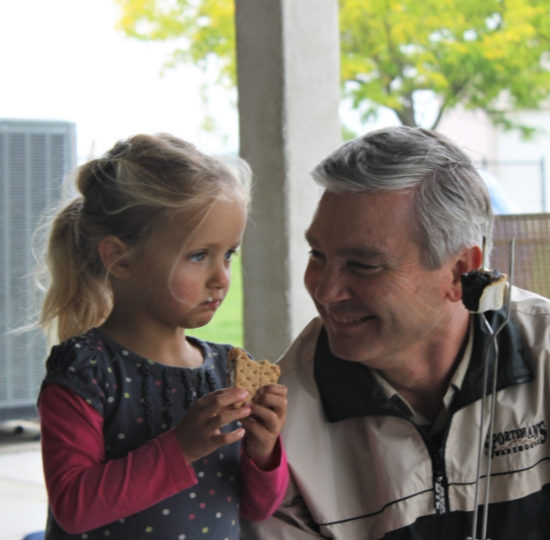 Dr. Floyd with his granddaughter holding a smores Creekside Dental